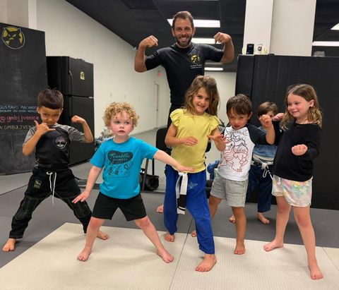 Mini Machados Kids BJJ students striking a pose with their coach at Gustavo Machado BJJ Venice